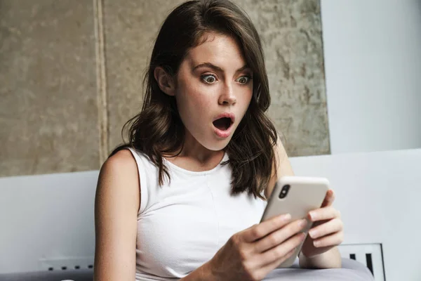 Afbeelding Van Brunette Geschokt Vrouw Met Behulp Van Smartphone Tijdens — Stockfoto