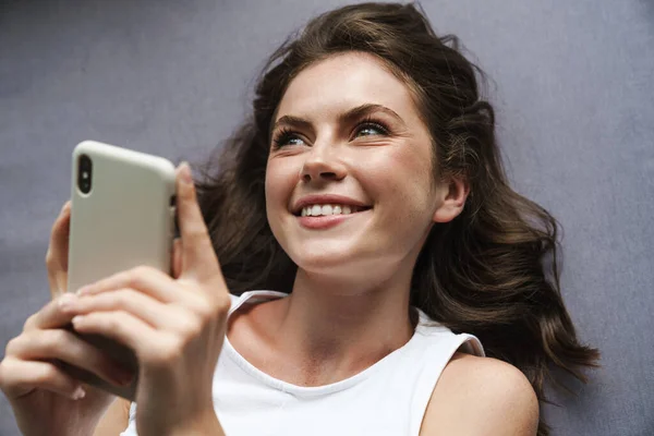Изображение Красивой Веселой Женщины Улыбающейся Пользующейся Мобильным Телефоном Лежащей Дома — стоковое фото