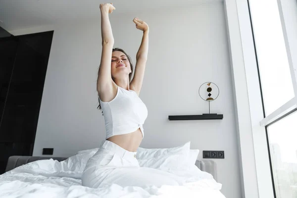 Imagen Joven Mujer Complacida Sonriendo Estirando Cuerpo Mientras Está Sentada —  Fotos de Stock