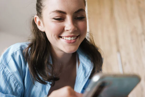 Foto Feliz Chica Agradable Sonriendo Usando Teléfono Móvil Mientras Está —  Fotos de Stock