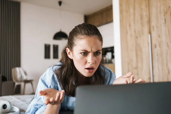 Fénykép Elégedetlen Kaukázusi Lány Használja Laptop Miközben Feküdt Ágyban Nappaliban — Stock Fotó