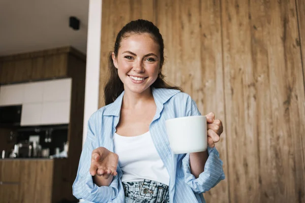 Imagem Uma Jovem Menina Feliz Positiva Casa Segurando Xícara Café — Fotografia de Stock