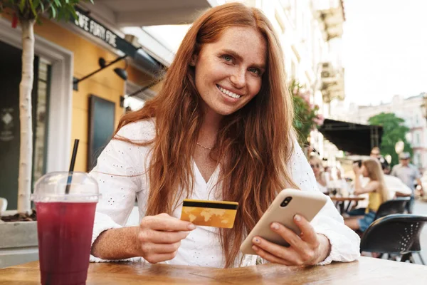 카페에 카드로 온라인 쇼핑을 아름답게 여자가 휴대폰을 사용하고 — 스톡 사진
