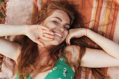 Yazlık elbiseli, battaniyeye uzanmış, selfie çeken genç bir kızın en iyi görüntüsü.