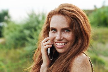 Yazlık elbiseli güzel bir kadın cep telefonuyla konuşuyor. Kırsal kesimde. Açık havada. Seyahat kavramı