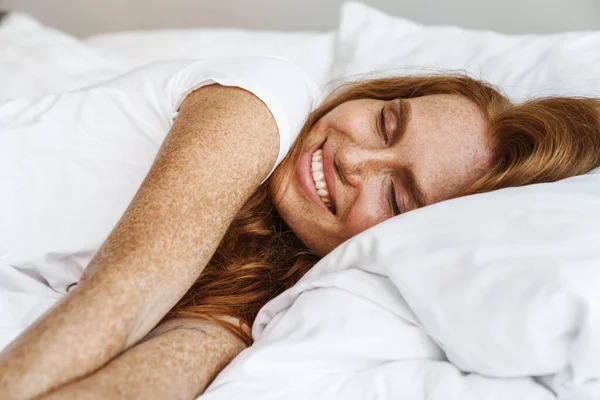 ベッドで家に寝ている間にカメラに向かって笑顔を浮かべるバカ女の姿 — ストック写真