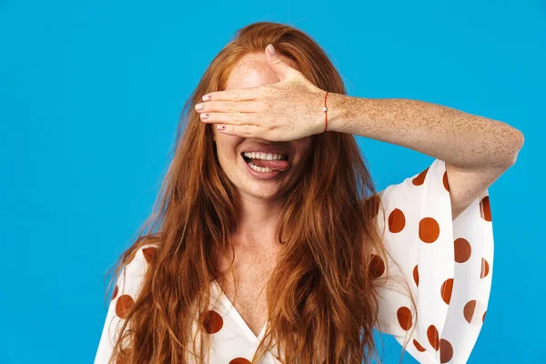 Uzun kızıl saçlı, güzel bir genç kadının portresi. Yazlık giysiler giyiyor. Mavi arka planda tek başına duruyor.