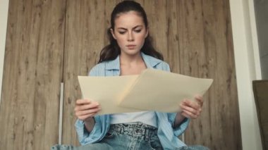 Yoğunlaşmış bir kadın evde otururken evrak işleriyle uğraşıyor.