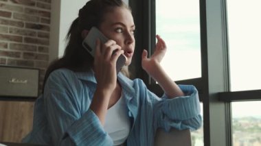 Hoş bir genç bayan evde akıllı telefonuyla konuşuyor.