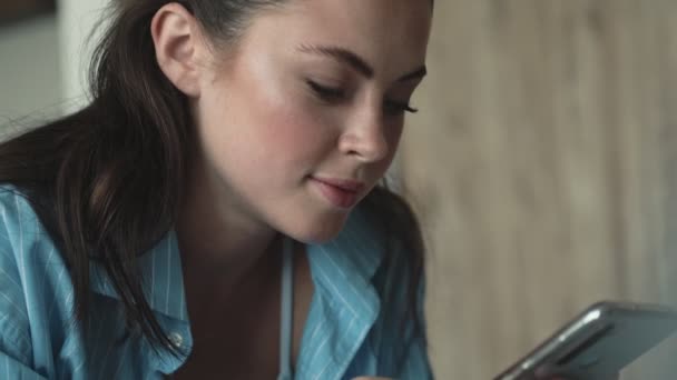 Зосереджена Жінка Використовує Свій Смартфон Лежачи Ліжку Вдома — стокове відео