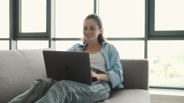 Una Joven Contenta Está Usando Computadora Portátil Sentada Sala Estar — Vídeo de stock