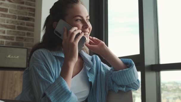 笑顔の若い女性が家でスマホで話している — ストック動画