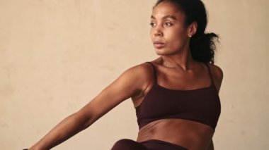 Genç Afrikalı fitness kadını germe egzersizleri yapıyor. Beyaz duvar arka planında izole edilmiş.