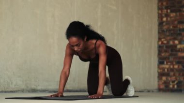 Genç Afrikalı fitness kadını beyaz duvar arka planında izole edilmiş spor tahtası egzersizi yapıyor.