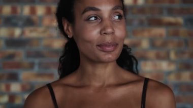 Genç Afrikalı mutlu spor kadın içeride poz veriyor ve kameraya bakıyor.