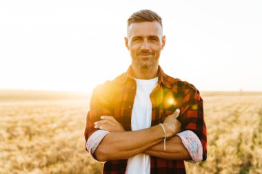 Mısır gevreği tarlasında dikilirken gülümseyen ve kameraya bakan yetişkin bir adamın görüntüsü