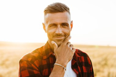 Mısır gevreği tarlasında dikilirken gülümseyen ve kameraya bakan yetişkin bir adamın görüntüsü