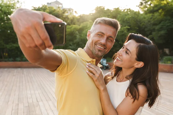 在夏季公园散步时 一对快乐的成年男女在手机上拍下自己的照片 拥抱对方的肖像 — 图库照片