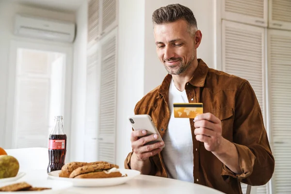 Bild Stilig Glad Man Som Håller Kreditkort Och Använder Smartphone — Stockfoto