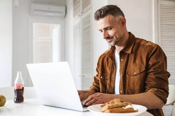 Imagen Del Hombre Guapo Complacido Trabajando Con Ordenador Portátil Sonriendo —  Fotos de Stock