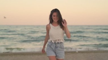 Güzel genç bir kız sahilde yürüyor.