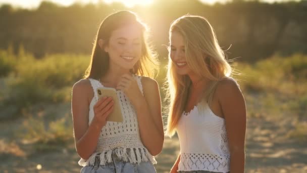 Dos Chicas Riendo Están Buscando Fotos Teléfono Inteligente Playa — Vídeos de Stock