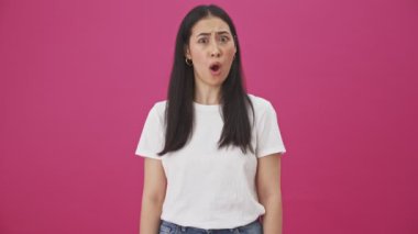 Ciddi bir kadın ellerini çapraz yapıyor. Pembe bir arka planda tek başına dikilip durmaktan vazgeçiyor.