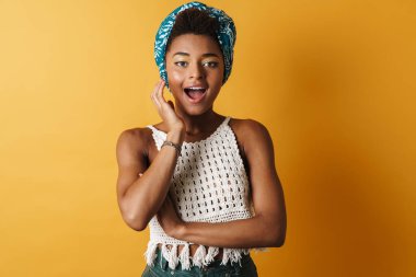 Heyecanlı Afrikalı Amerikalı kadın görüntüsü. Kamera karşısında şaşırdığını belirtiyor. Sarı arka plan izole edilmiş.