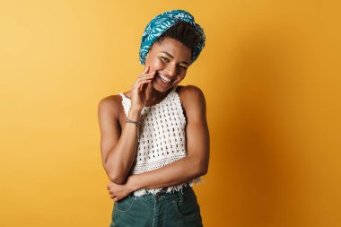 Kamera önünde poz veren ve gülen neşeli Afro-Amerikan kadın görüntüsü izole edilmiş sarı arka plan
