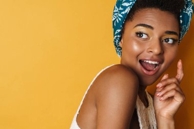 Heyecanlı Afrikalı Amerikalı kadın görüntüsü. Kamera karşısında şaşırdığını belirtiyor. Sarı arka plan izole edilmiş.