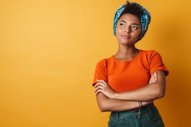 Mutlu Afro-Amerikan kadın görüntüsü poz veren ve yukarı bakan izole sarı arka plan