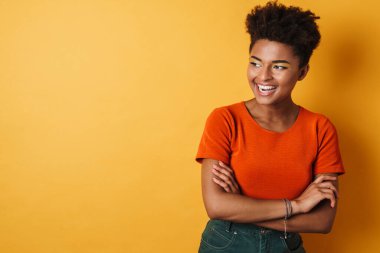 Kamerada poz veren ve gülen neşeli Afro-Amerikan kadın görüntüsü izole edilmiş sarı arka plan