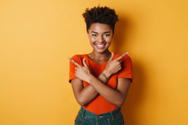 Neşeli bir Afrikalı Amerikalı kadının farklı tarafları göstermesi ve izole edilmiş sarı arka planda gülümsemesi.