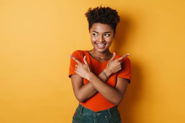 Neşeli bir Afrikalı Amerikalı kadının farklı tarafları göstermesi ve izole edilmiş sarı arka planda gülümsemesi.