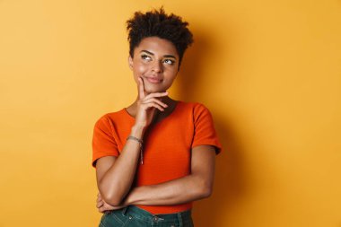 Mutlu Afro-Amerikan kadın görüntüsü. Düşünen ve yukarı bakan izole edilmiş sarı arka plan.