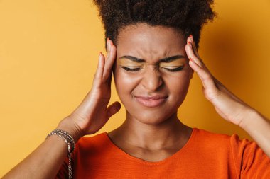 Kamera karşısında baş ağrısı olan mutsuz bir Afrikalı Amerikalı kadın görüntüsü izole edilmiş sarı arka plan.