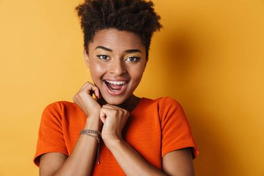 Heyecanlı Afrikalı Amerikalı kadın görüntüsü. Kamera karşısında şaşırdığını belirtiyor. Sarı arka plan izole edilmiş.