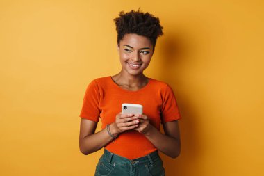 Gülümseyen ve cep telefonu kullanan neşeli Afrikalı Amerikalı kadın görüntüsü