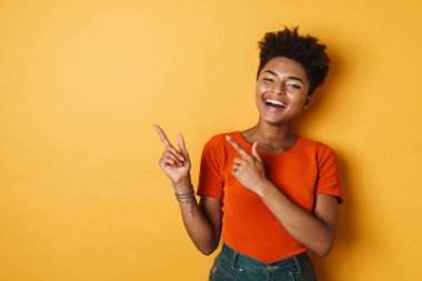Afro-Amerikalı neşeli bir kadının, parmaklarını bir kenara koyup, gülüşü izole edilmiş sarı arka plan.