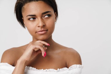 Beyaz arka planda izole edilmiş bir şekilde poz veren ve yan bakan Afro-Amerikan kadın.