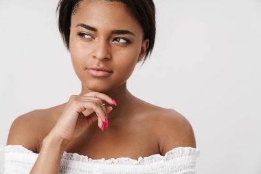 Beyaz arka planda izole edilmiş bir şekilde poz veren ve yan bakan Afro-Amerikan kadın.