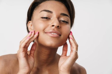 Beyaz arka planda izole edilmiş, gülümseyen ve kameraya bakan yarı çıplak Afro-Amerikan kadını.