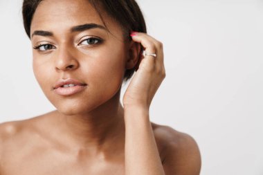 Beyaz arka planda izole edilmiş, poz veren ve kameraya bakan yarı çıplak Afrikalı Amerikalı kadın.