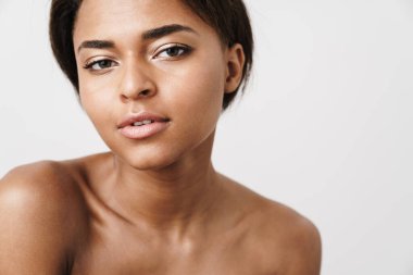 Beyaz arka planda izole edilmiş, poz veren ve kameraya bakan yarı çıplak Afrikalı Amerikalı kadın.