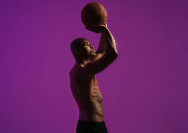 非洲裔美国人在紫色墙壁上打篮球的半裸形象 — 图库照片