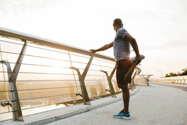 Rahat Afrikalı sporcu köprüde dikilirken geriniyor.