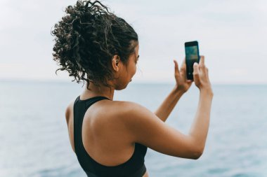 Genç Afro-Amerikan sporcunun gezinti alanında cep telefonuyla fotoğraf çekmesi