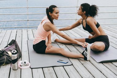 Çok uluslu sporcu kadınların gezinti güvertesindeki minderlerde çalışmalarının görüntüsü