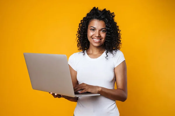 照片中快乐的非洲裔美国女人笑着用笔记本电脑隔离在黄色背景下 — 图库照片