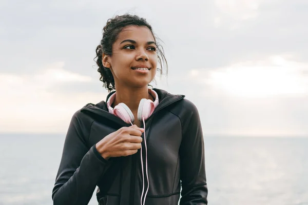 산책로를 걷다가 헤드폰을 채웃고 아프리카계 미국인젊은 여성의 — 스톡 사진